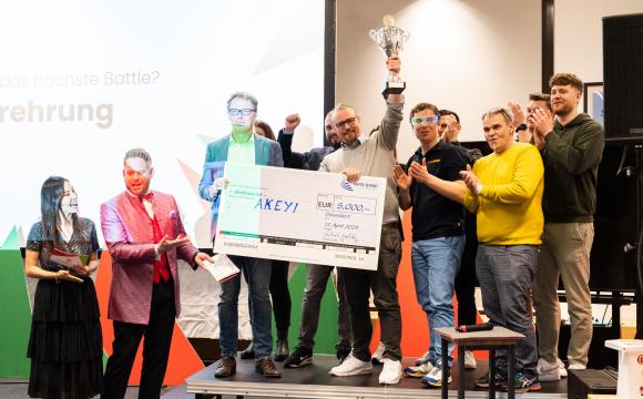 AKEYI-Gründer Stephan Egbringhoff (mit Pokal) und Oliver Holz (dahinter) freuen sich über Titel, Preisgeld und Trophäe.